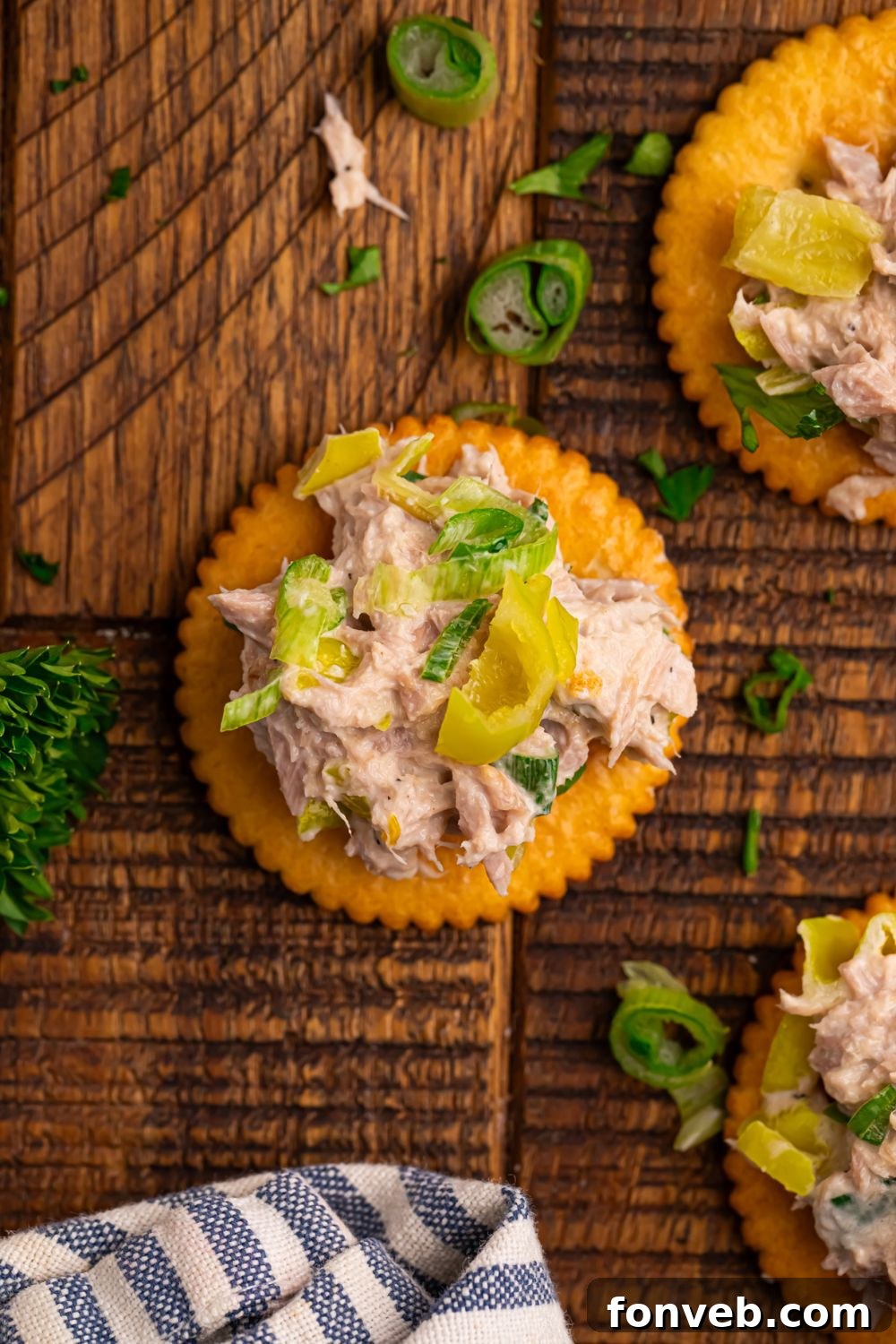 Pepperoncini Ranch Tuna Salad on top of crackers with parsley and green onions on table 