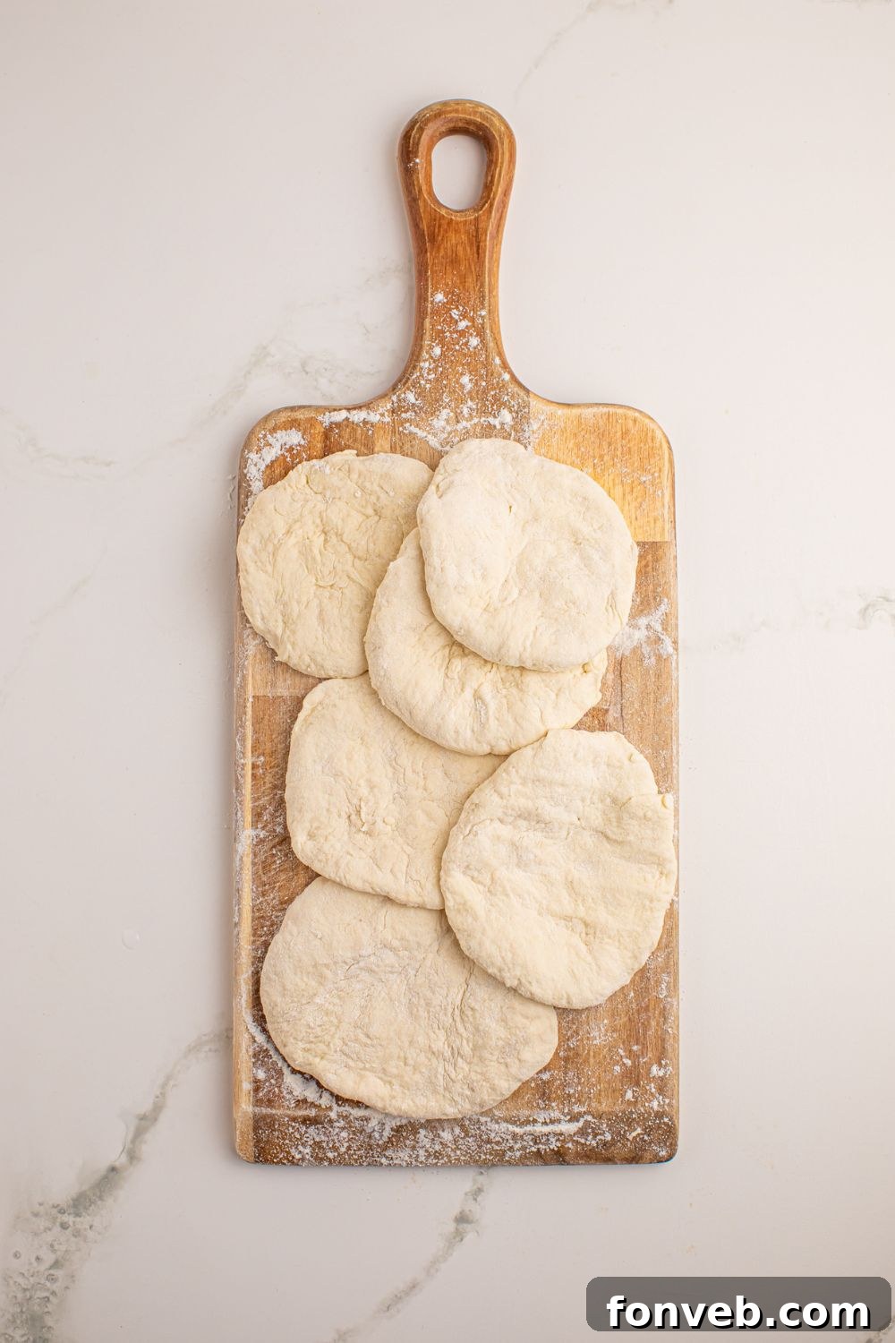 3-Ingredient Flatbread dough pieces rolled into uniform circles on a cutting board