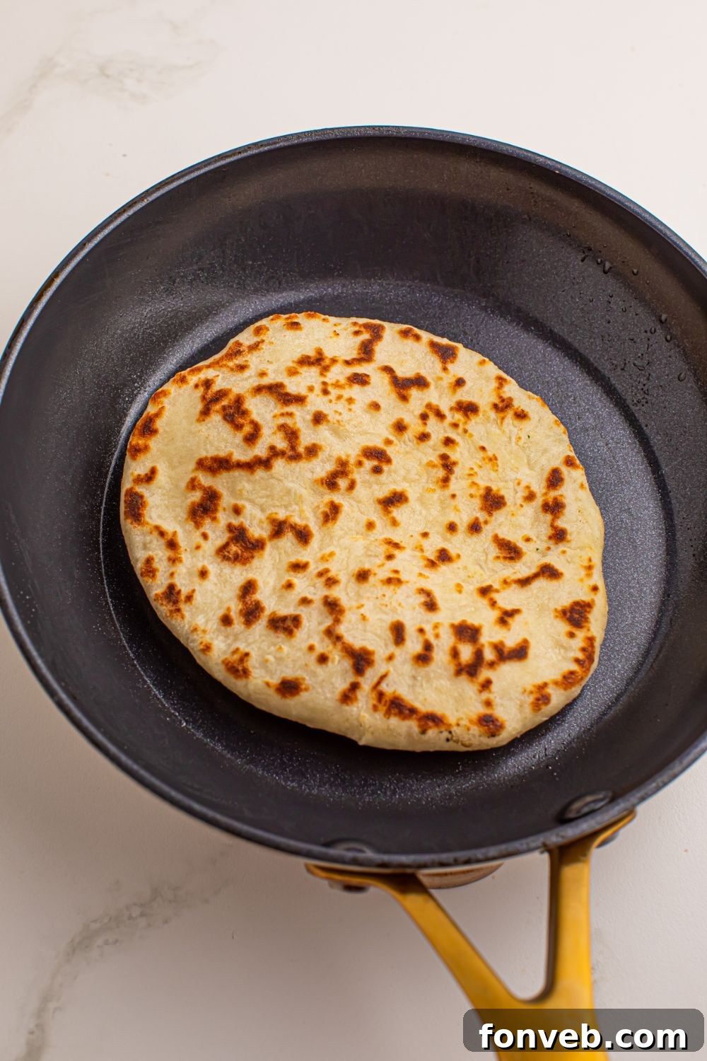 A 3-Ingredient Flatbread cooking in a hot skillet, browning and puffing up