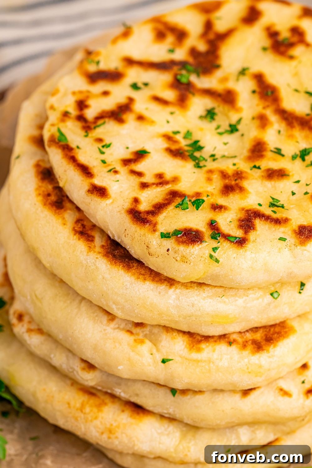 A stack of 3-Ingredient Flatbreads on a table, with fresh parsley and a knob of butter nearby