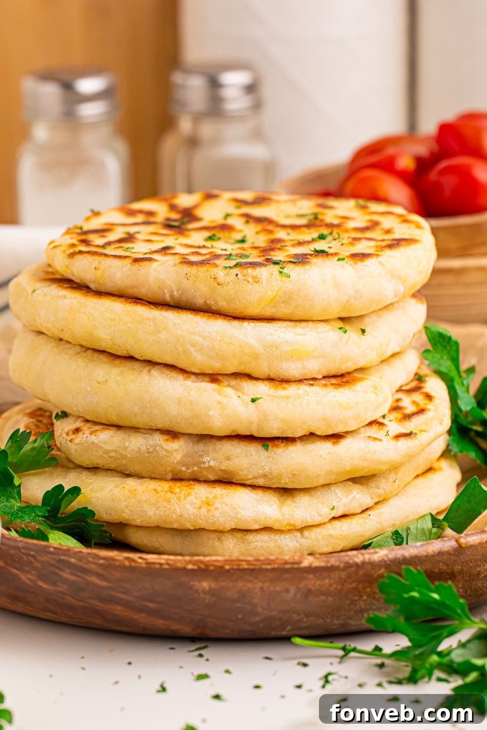 A stack of 3-Ingredient Flatbreads with parsley, and a bowl of cherry tomatoes in the background