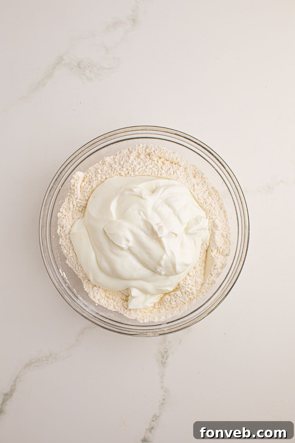 3-Ingredient Flatbread dough being mixed in a bowl with Greek yogurt in the center