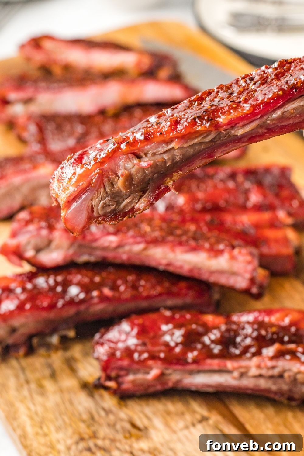 Grilled BBQ Baby Back Ribs on cutting board with one being held
