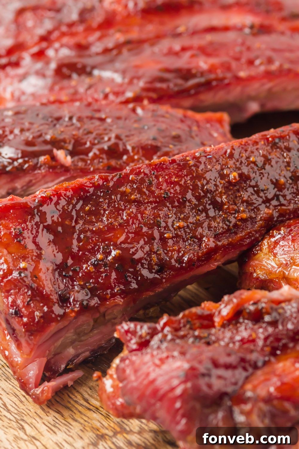 Grilled BBQ Baby Back Ribs cut into strips on a wooden cutting board