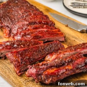 Grilled BBQ Baby Back Ribs placed on cutting board with part of them cut