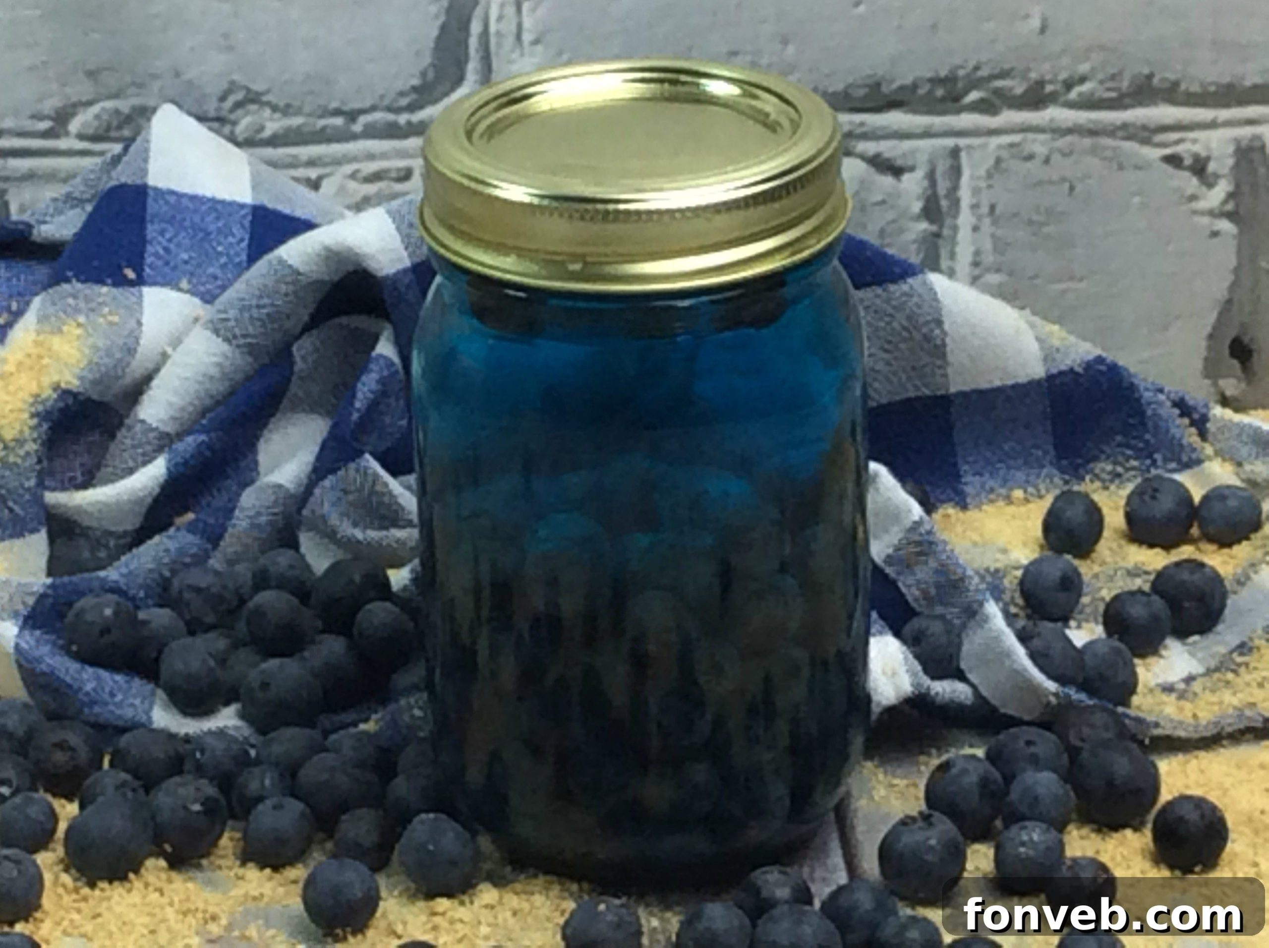 Close-up of a mason jar filled with Blueberry Cobbler Moonshine, garnished with blueberries
