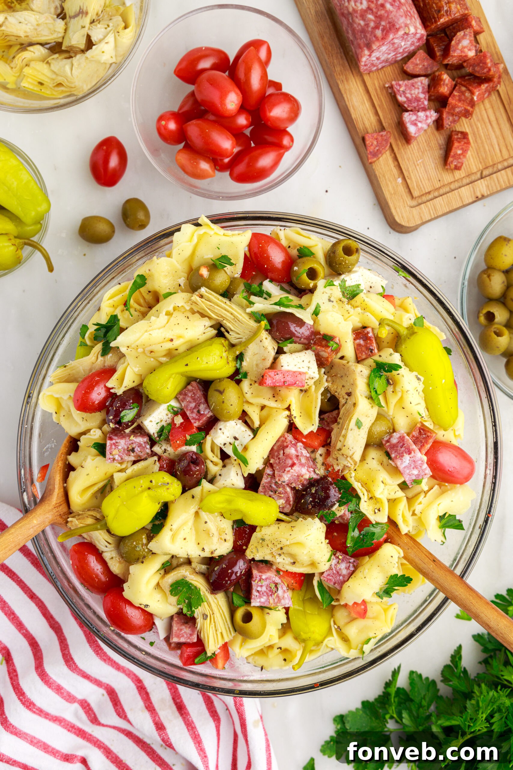 Antipasto Tortellini Pasta Salad in a bowl surrounded by the ingredients 