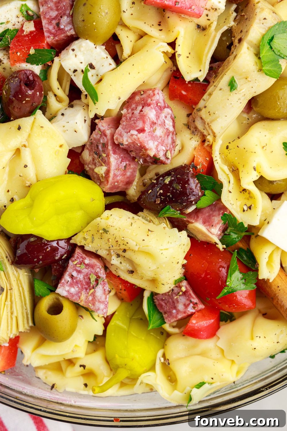 Antipasto Tortellini Pasta Salad in a bowl with a close up on tortellini and other ingredients 