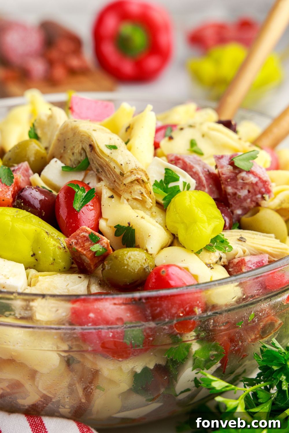 side view of Antipasto Tortellini Pasta Salad in a glass bowl with spoons inside 