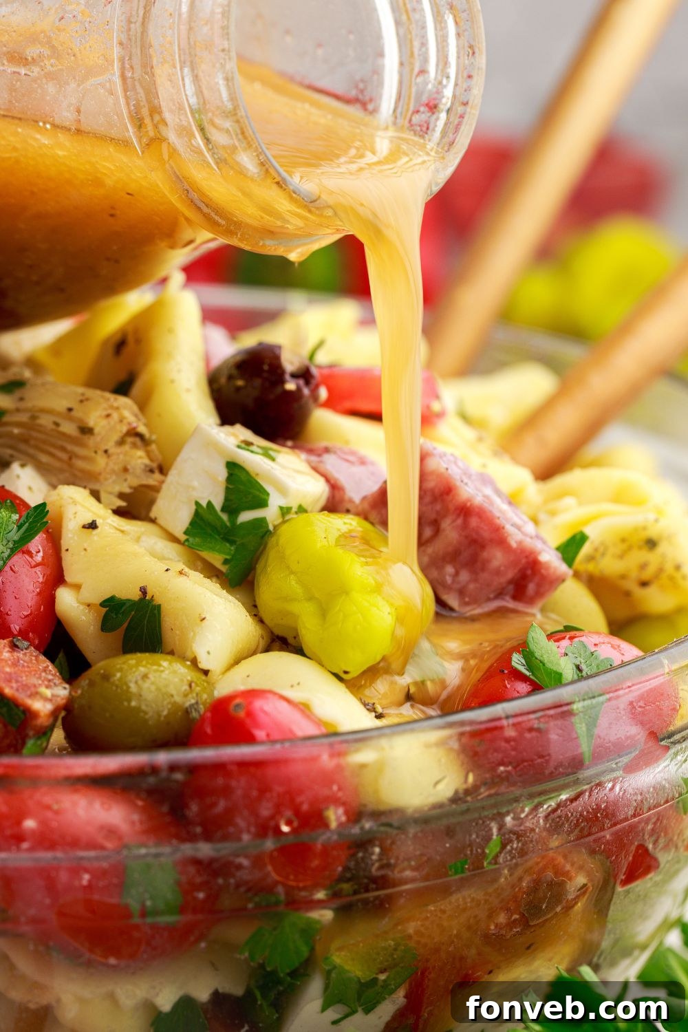 pouring dressing into a bowl of Antipasto Tortellini Pasta Salad