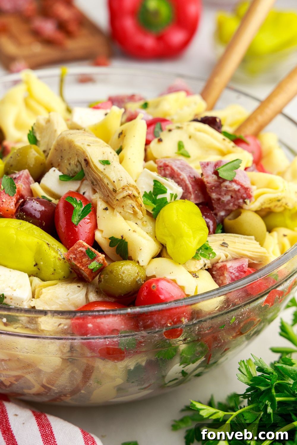 Antipasto Tortellini Pasta Salad in a glass bowl with spoons in the bowl 