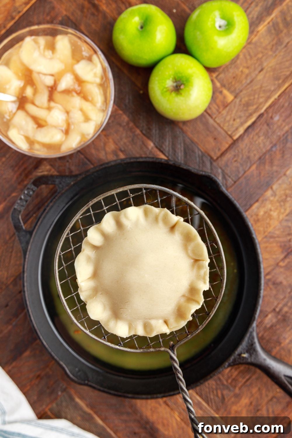 Golden Glazed Apple Hand Pies 11 Deep Fried Apple Hand Pie in a ladle above pot with hot oil and apples to the side