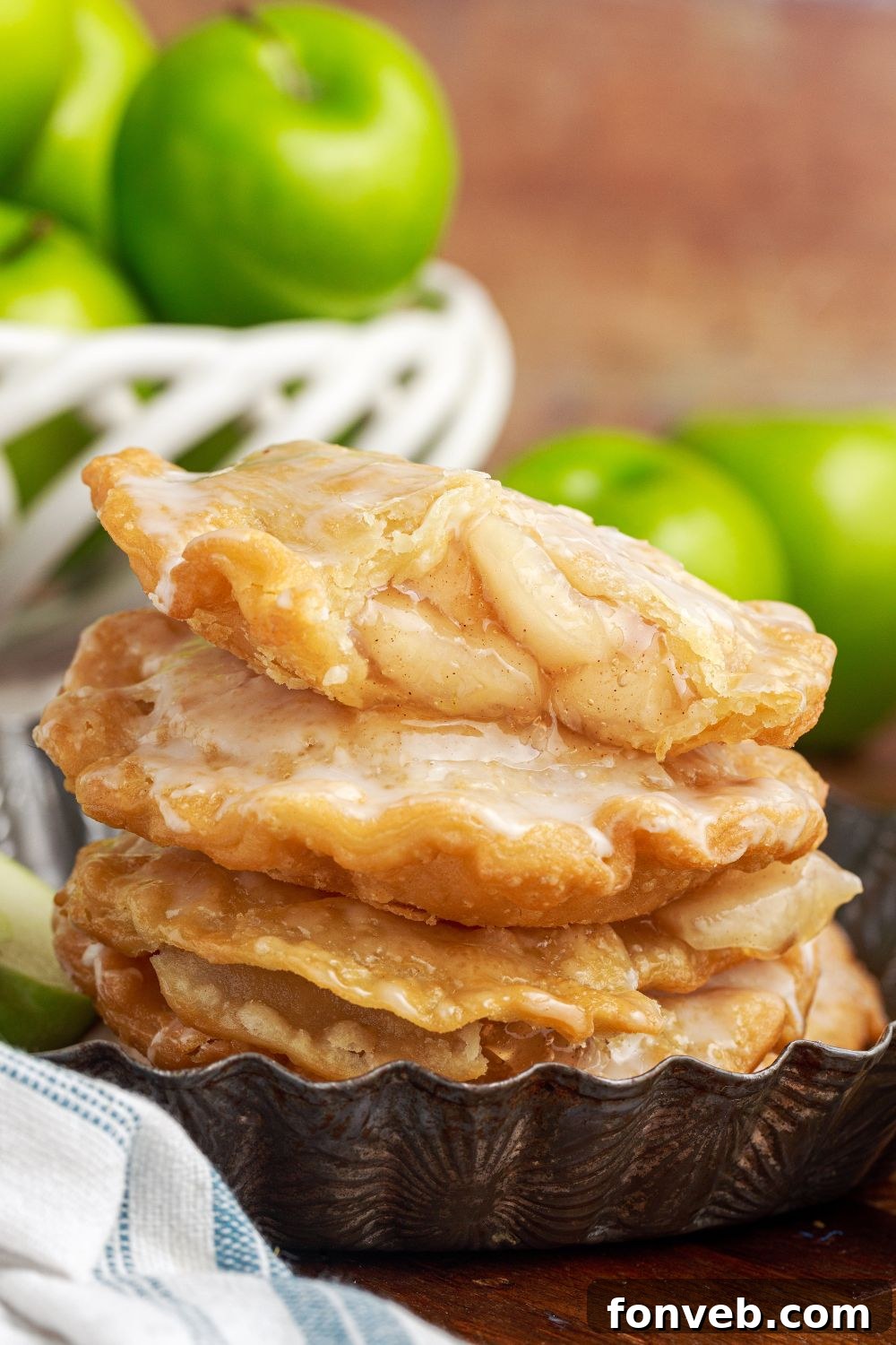 Golden Glazed Apple Hand Pies 15 Deep Fried Apple Hand Pies stacked on table with apples in a bowl and apples to side