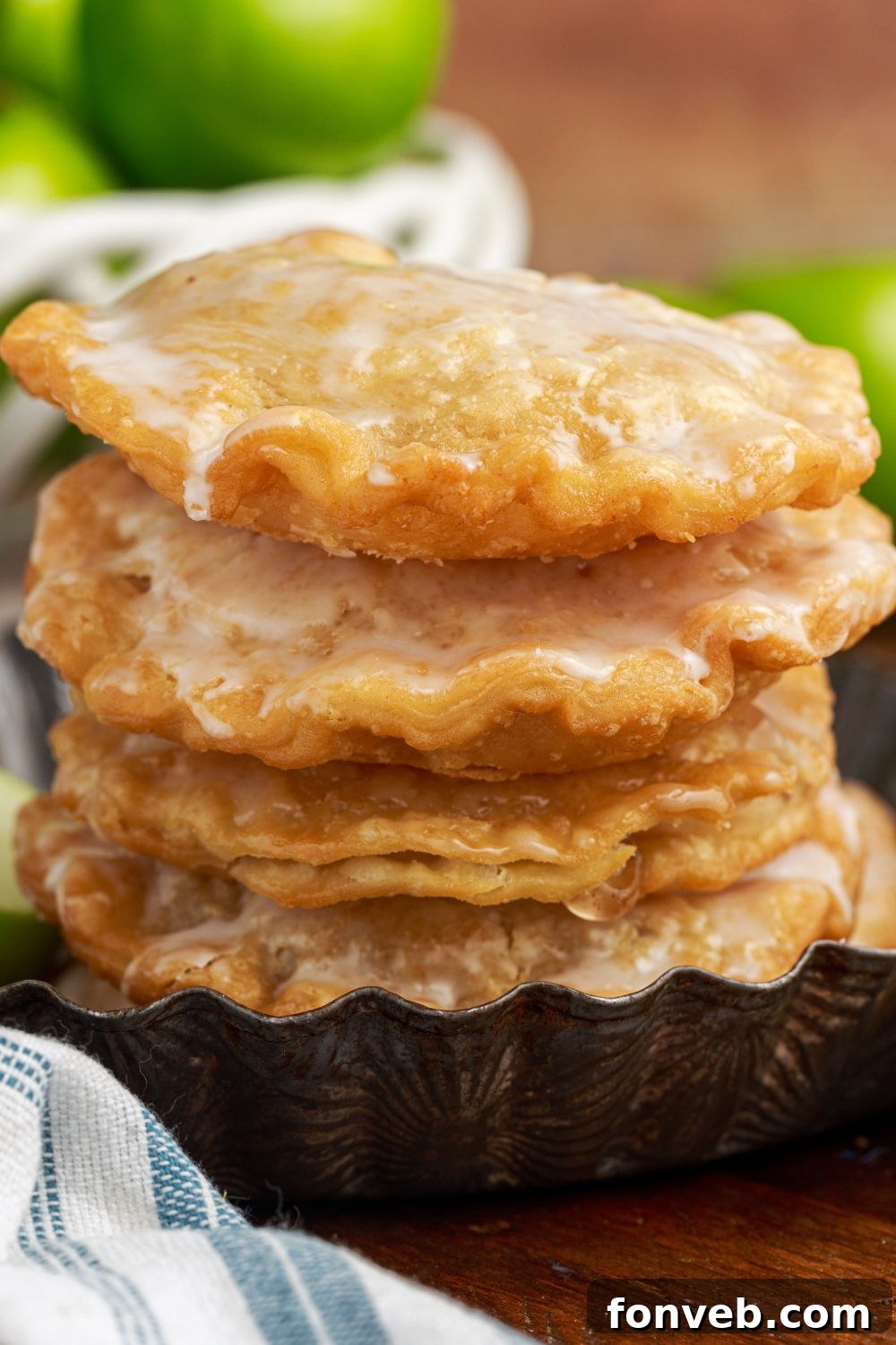 Golden Glazed Apple Hand Pies 20 Deep Fried Apple Hand Pies stacked on table with more apples to side and towel in front