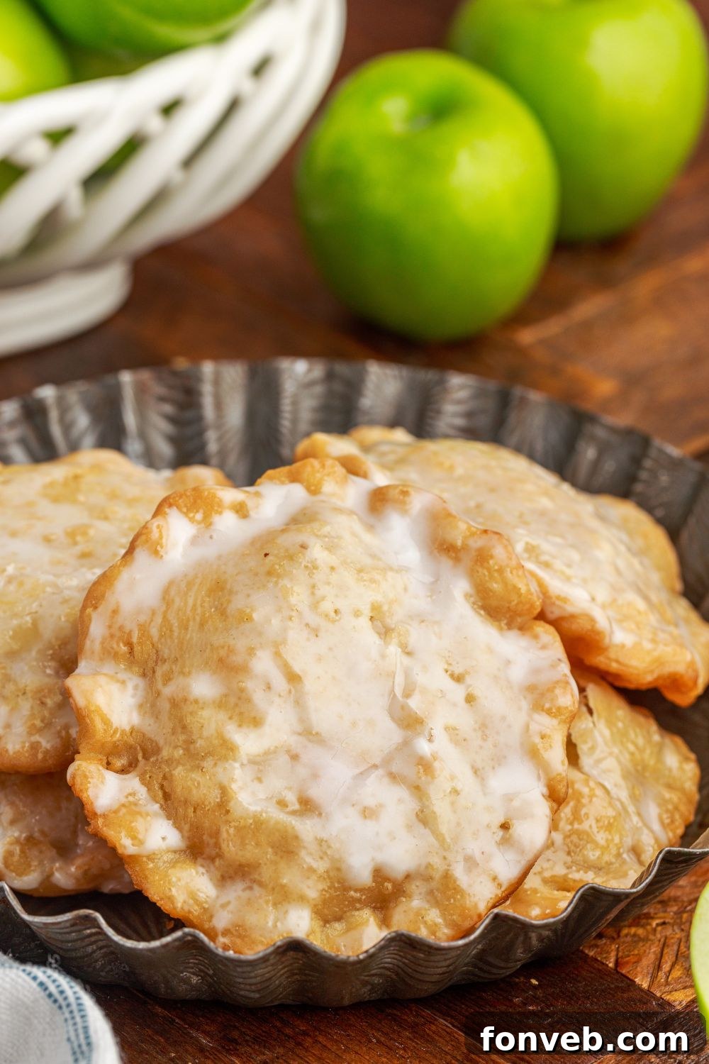 Golden Glazed Apple Hand Pies 21 Deep Fried Apple Hand Pies on a plate with a bowl of apples to the side to show glazed hand pies