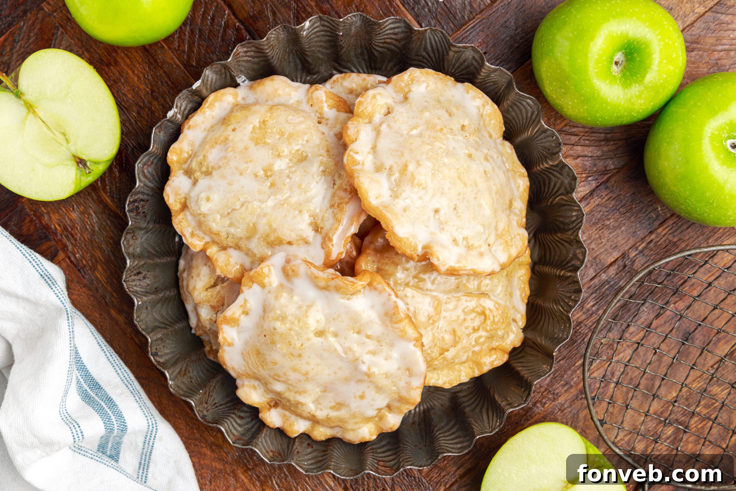 Golden Glazed Apple Hand Pies 22 Deep Fried Apple Hand Pies spread around table with apples to side and a bowl of glaze to side