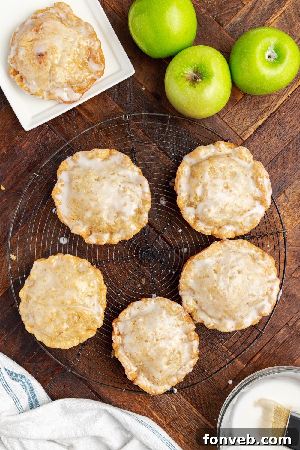 Golden Glazed Apple Hand Pies 23 Deep Fried Apple Hand Pies spread around table with apples to side and a bowl of glaze to side