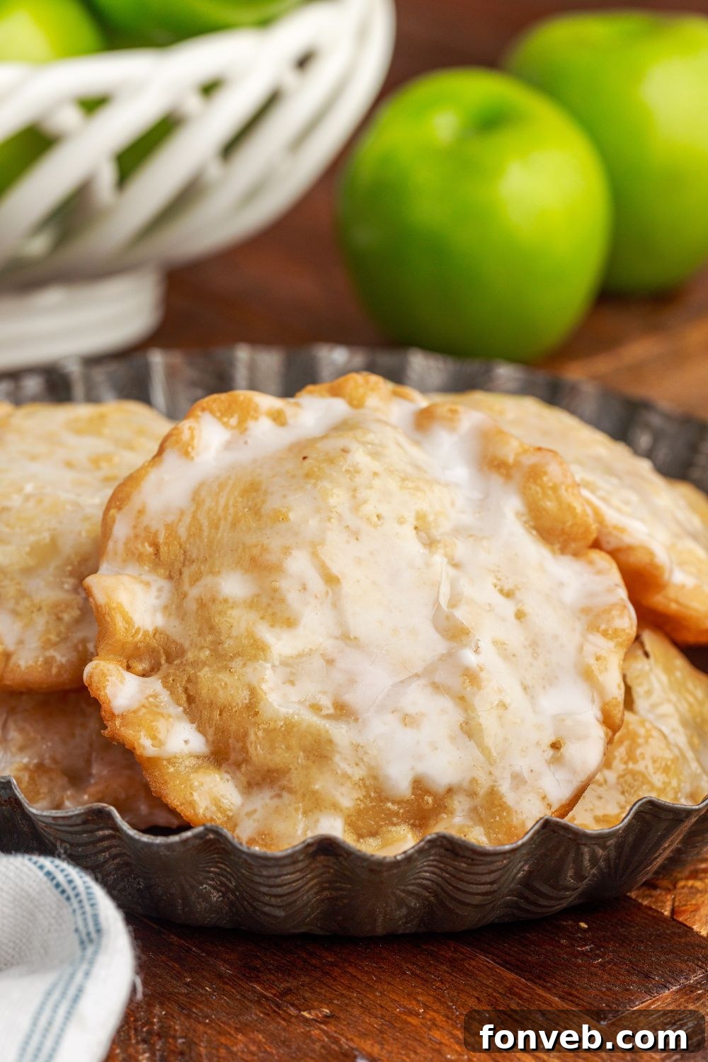 Golden Glazed Apple Hand Pies 5 Deep Fried Apple Hand Pies piled on a plate with green apples in background