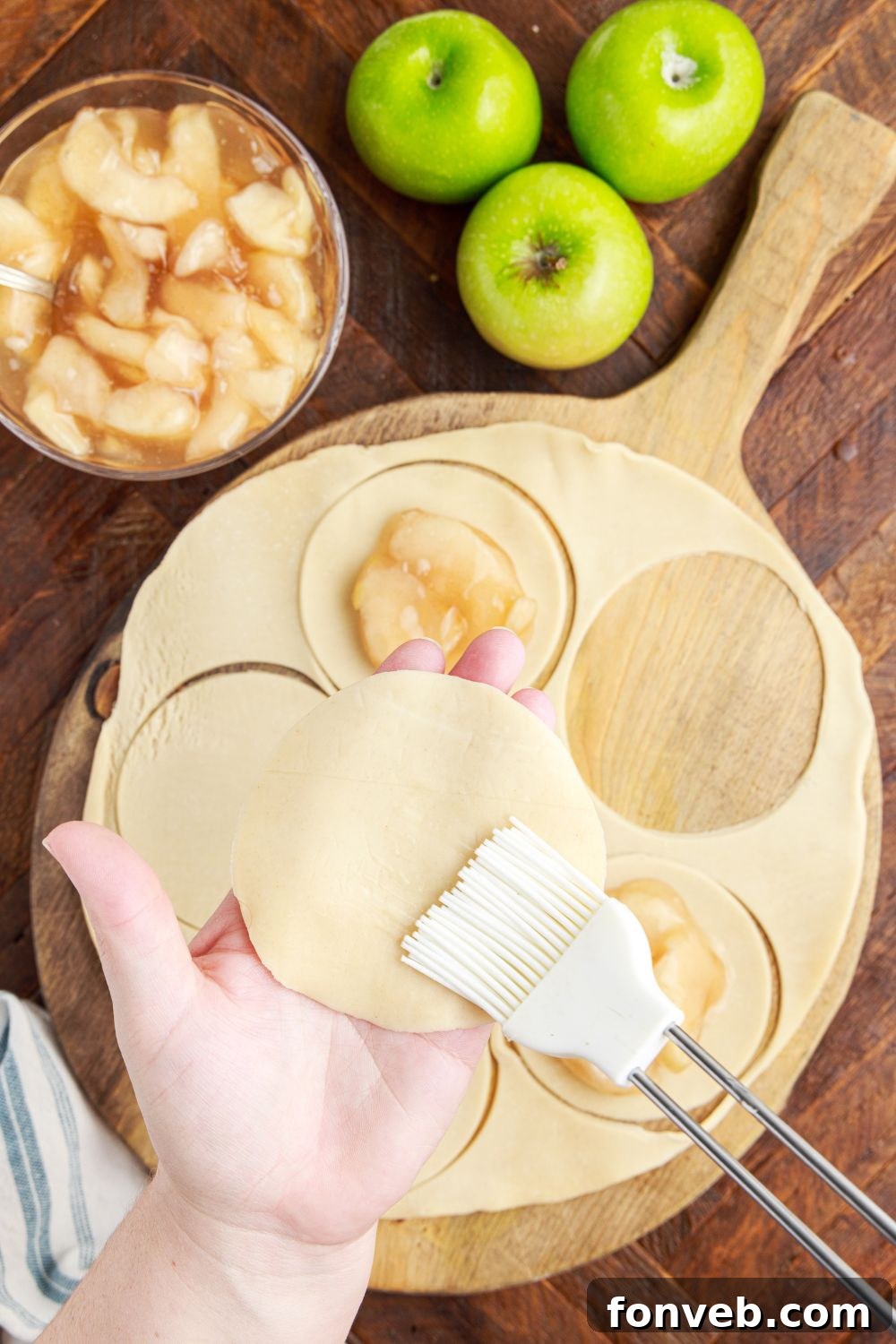 Golden Glazed Apple Hand Pies 9 Deep Fried Apple Hand Pies being made on table being brushed and pie filling in circles