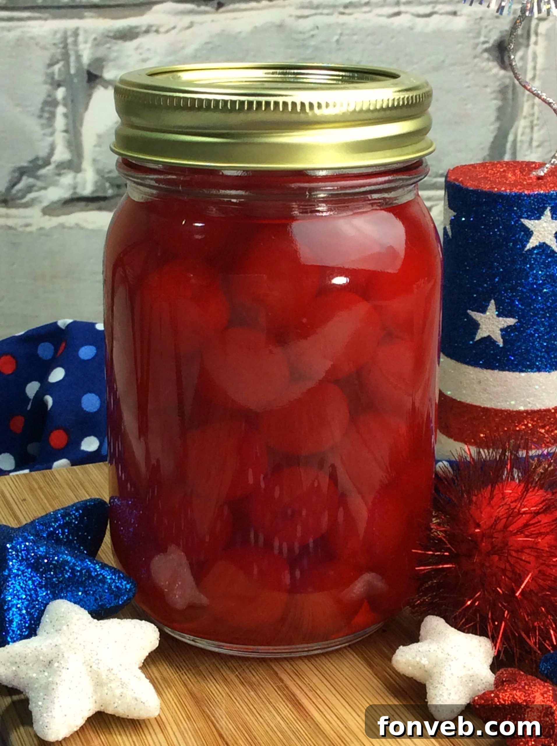 A person holding a jar of cherry moonshine, with a blurred background suggesting a home environment.