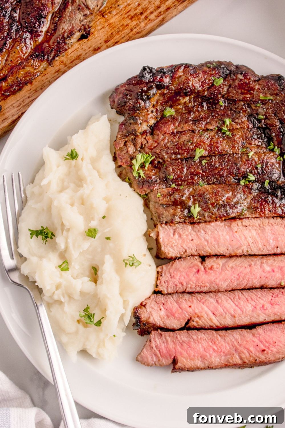 Grilled Ribeye Steak on plate with mashed potatoes to side and a fork on side of plate 