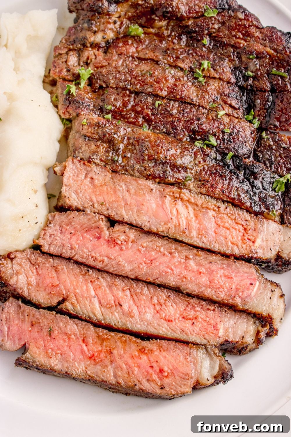 overhead look of sliced steak on plate with mashed potatoes to the side of plate 