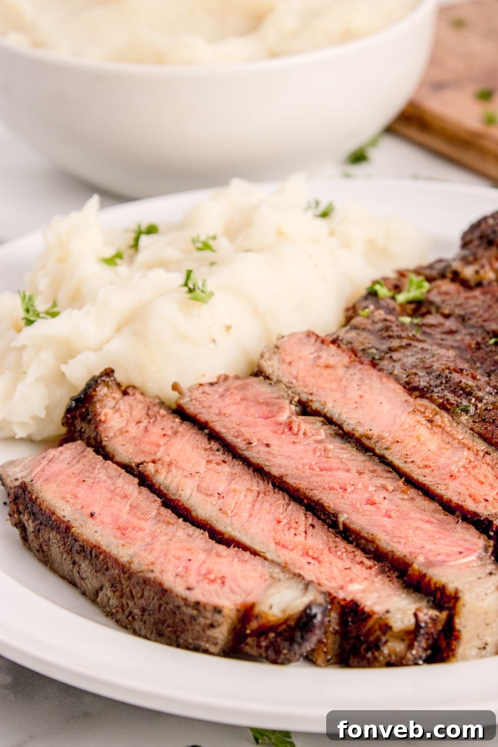 side view of plate with a sliced Grilled Ribeye Steak and potatoes on plate 