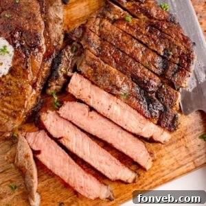 Grilled Ribeye Steak sliced on cutting board with a whole steak to side