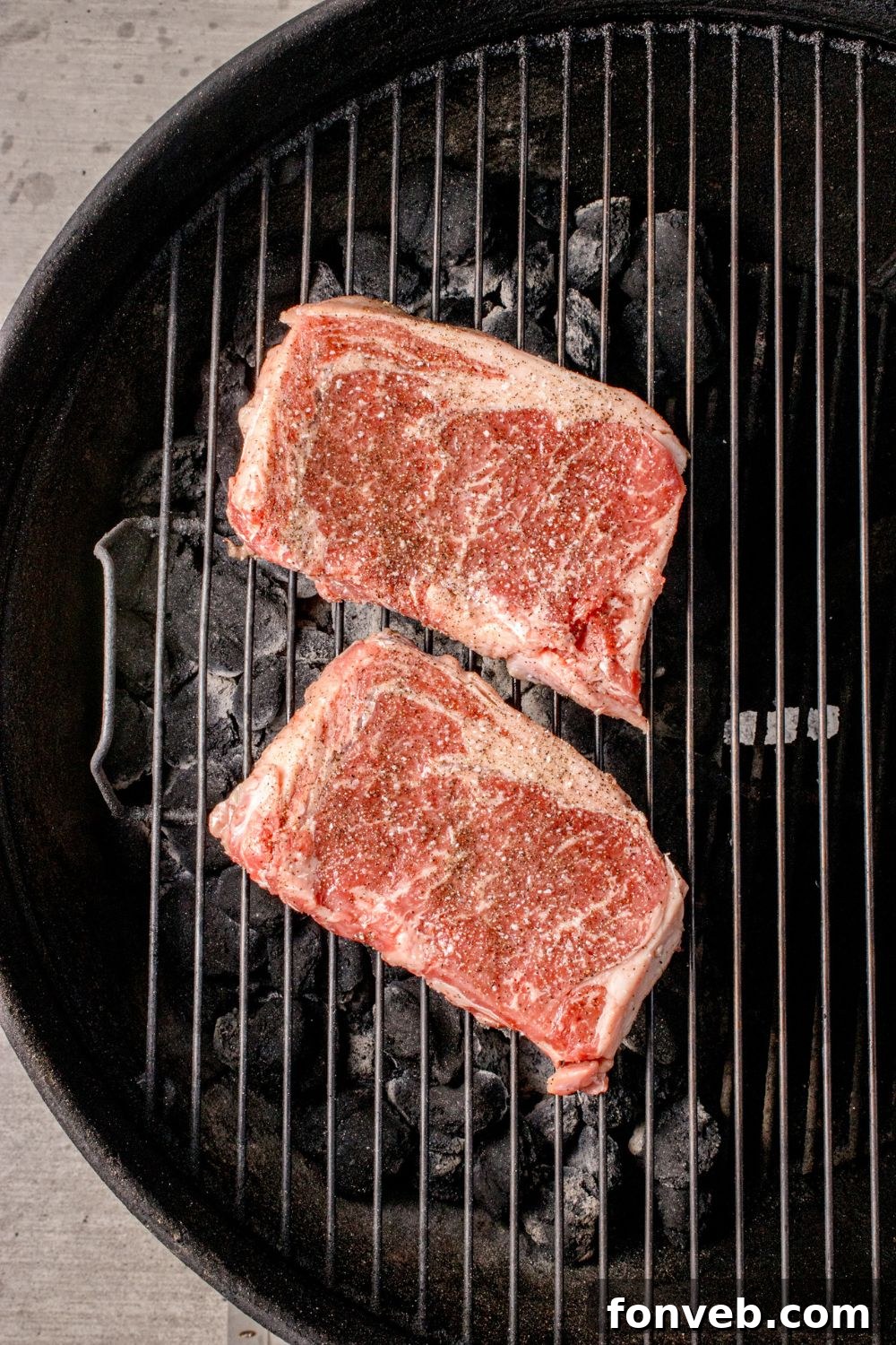 raw Ribeye Steaks on a charcoal grill