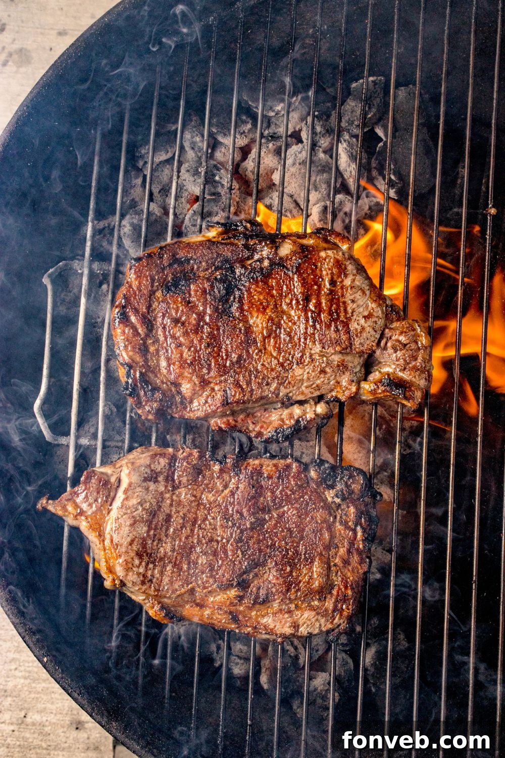 Grilled Ribeye Steaks cooking on a charcoal grill 