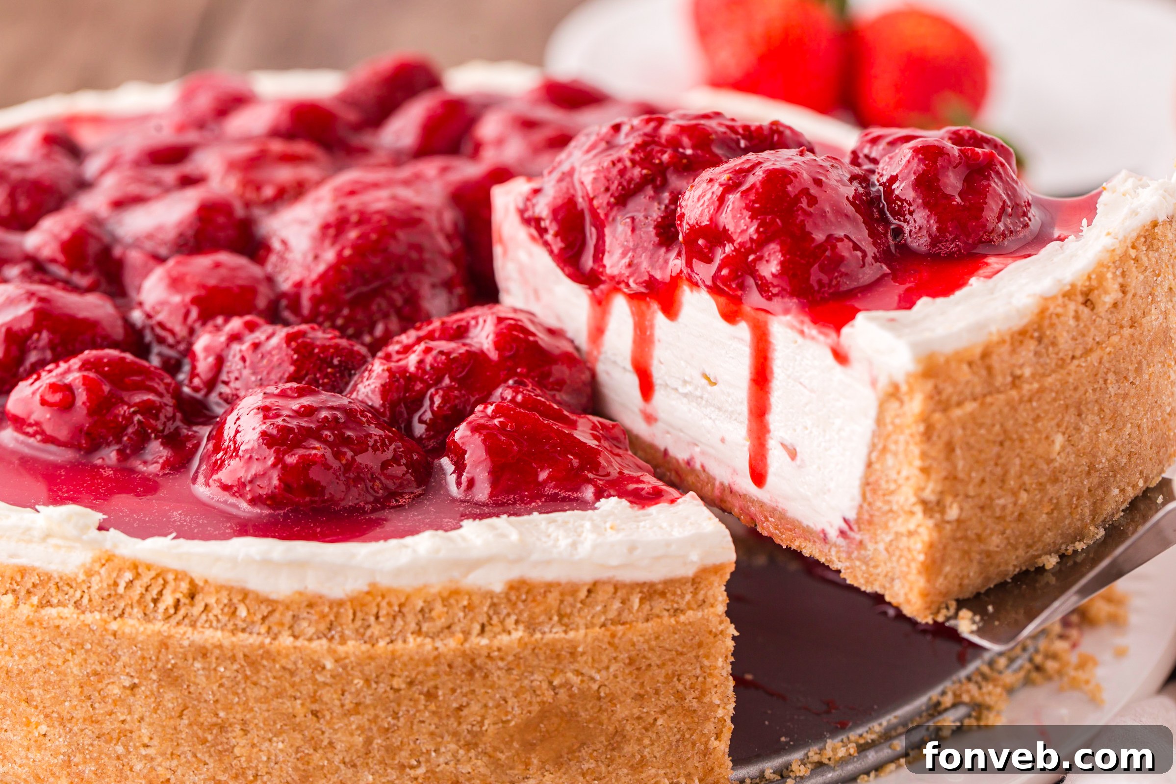 No Bake Strawberry Cheesecake being lifted out of pan with strawberries dripping down side of sliced cheesecake 