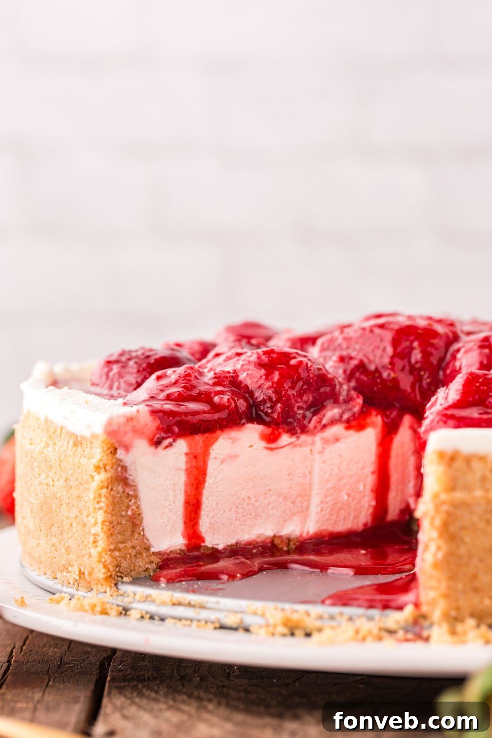 view of strawberry cheesecake on platter with some slices taken out to show how thick the cheesecake is