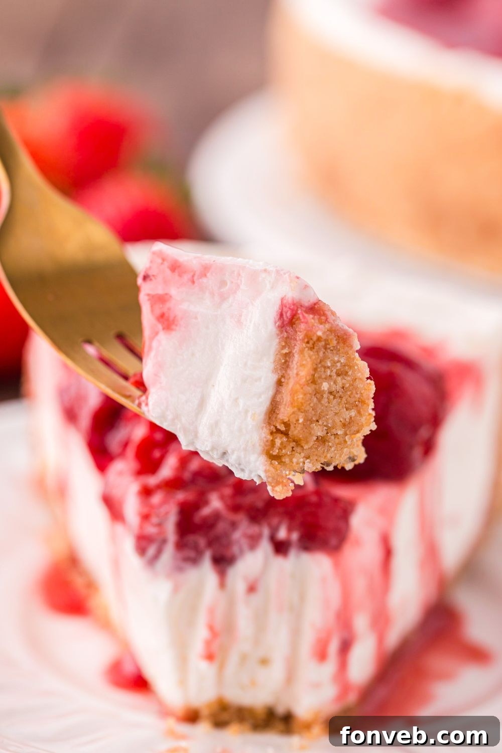 slice of No Bake Strawberry Cheesecake on plate with a fork with a bite on it 