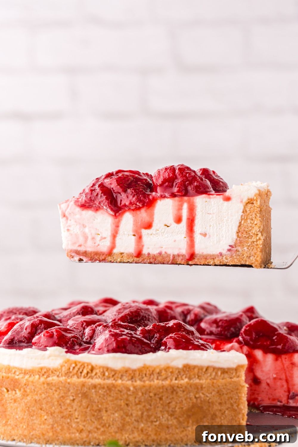 No Bake Strawberry Cheesecake on a spatula being lifted out to show the perfect slice of cheesecake 