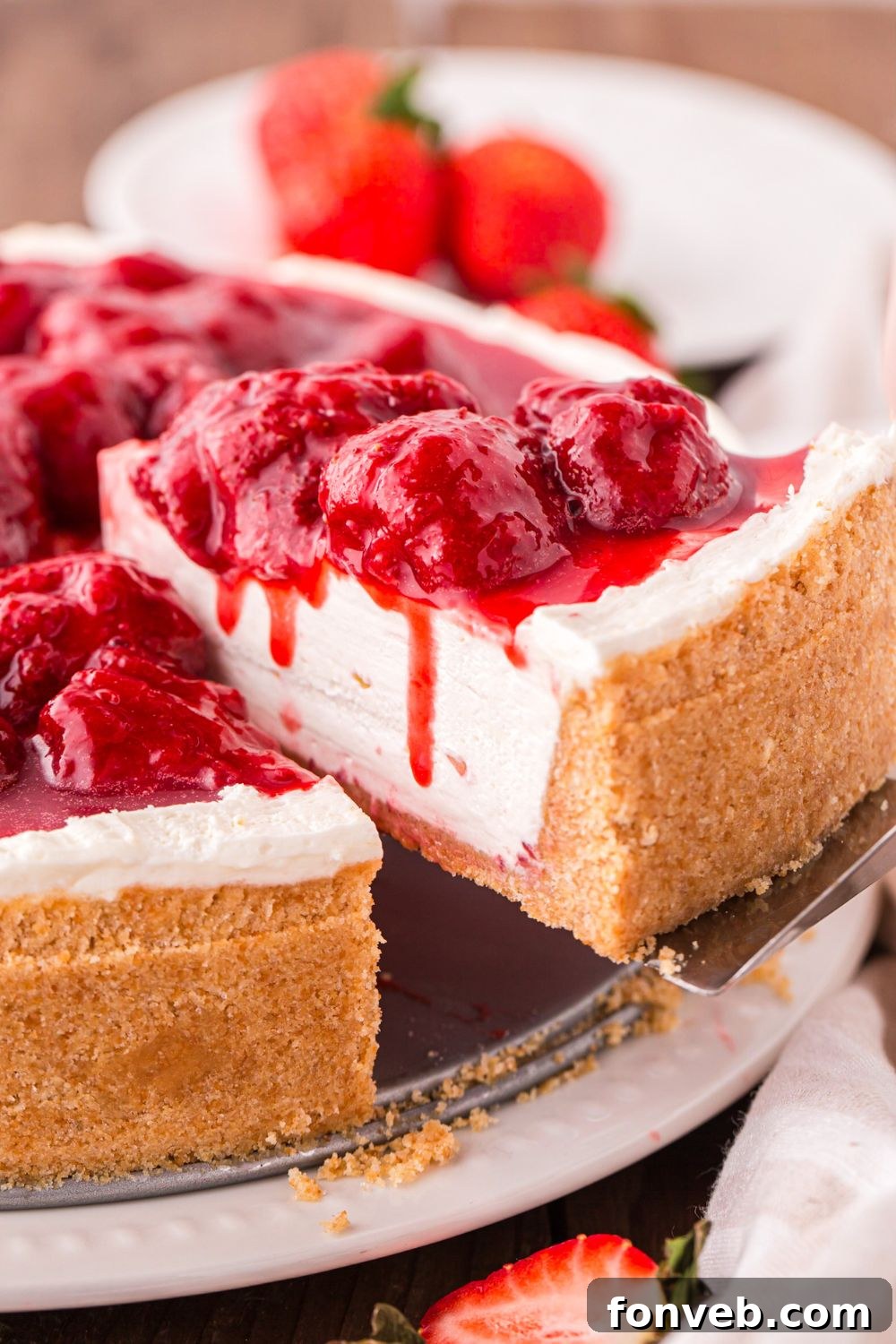 No Bake Strawberry Cheesecake on table with a slice being lifted out of the cheesecake 