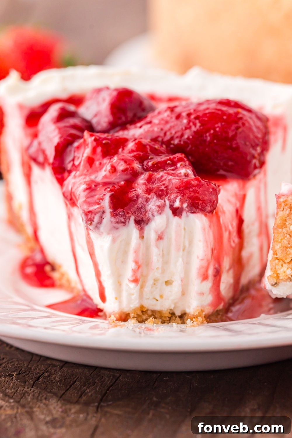a single slice of No Bake Strawberry Cheesecake on a plate with a bite taken out of it 