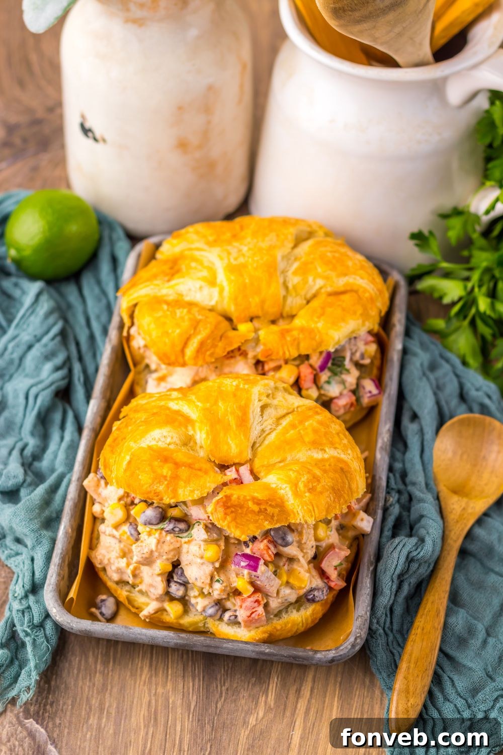overhead look of table with Creamy Taco Chicken Salad sandwiches on tray and lime and cilantro to side 