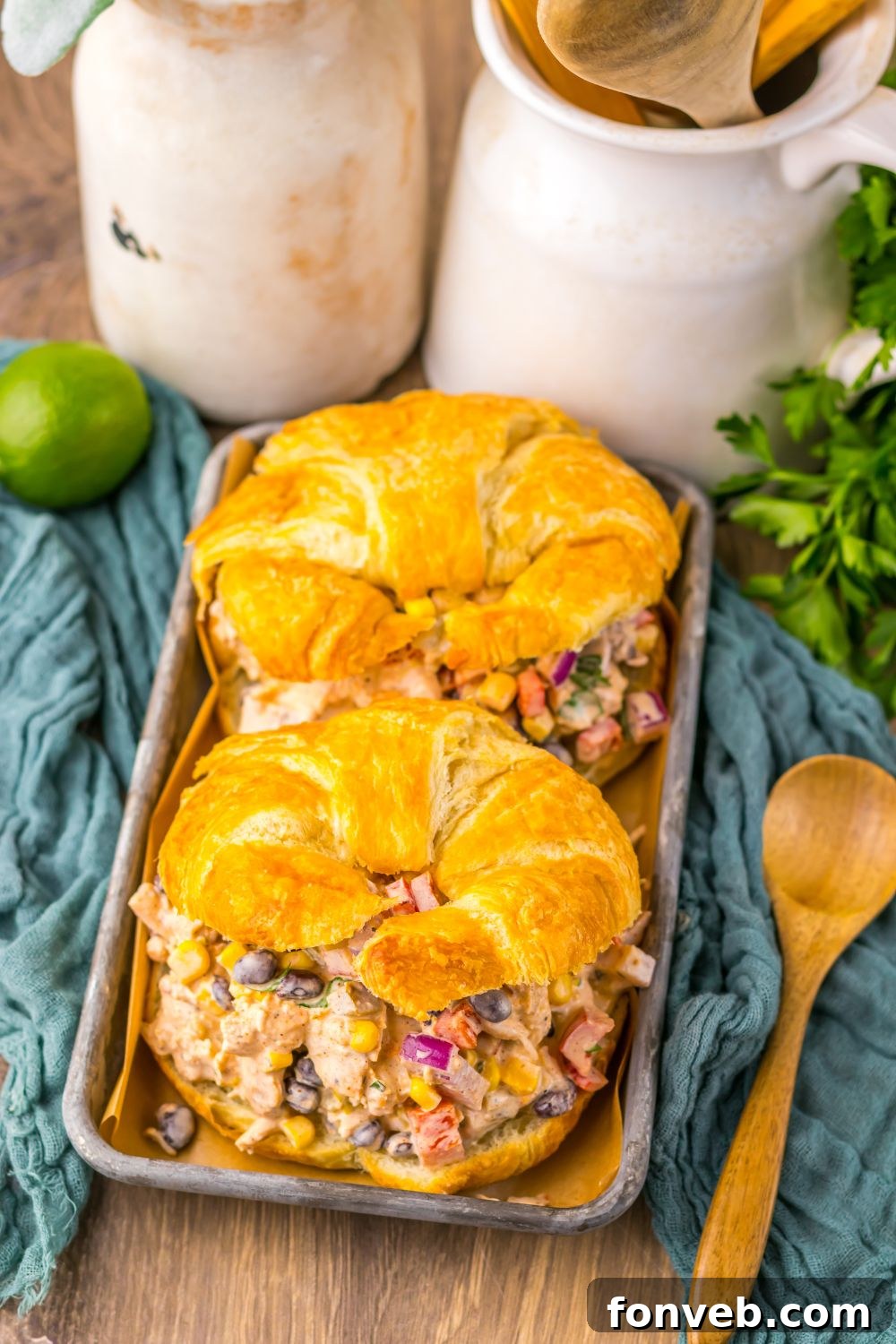 Creamy Taco Chicken Salad sandwiches on table with a towel under, lime, cilantro and more around table 