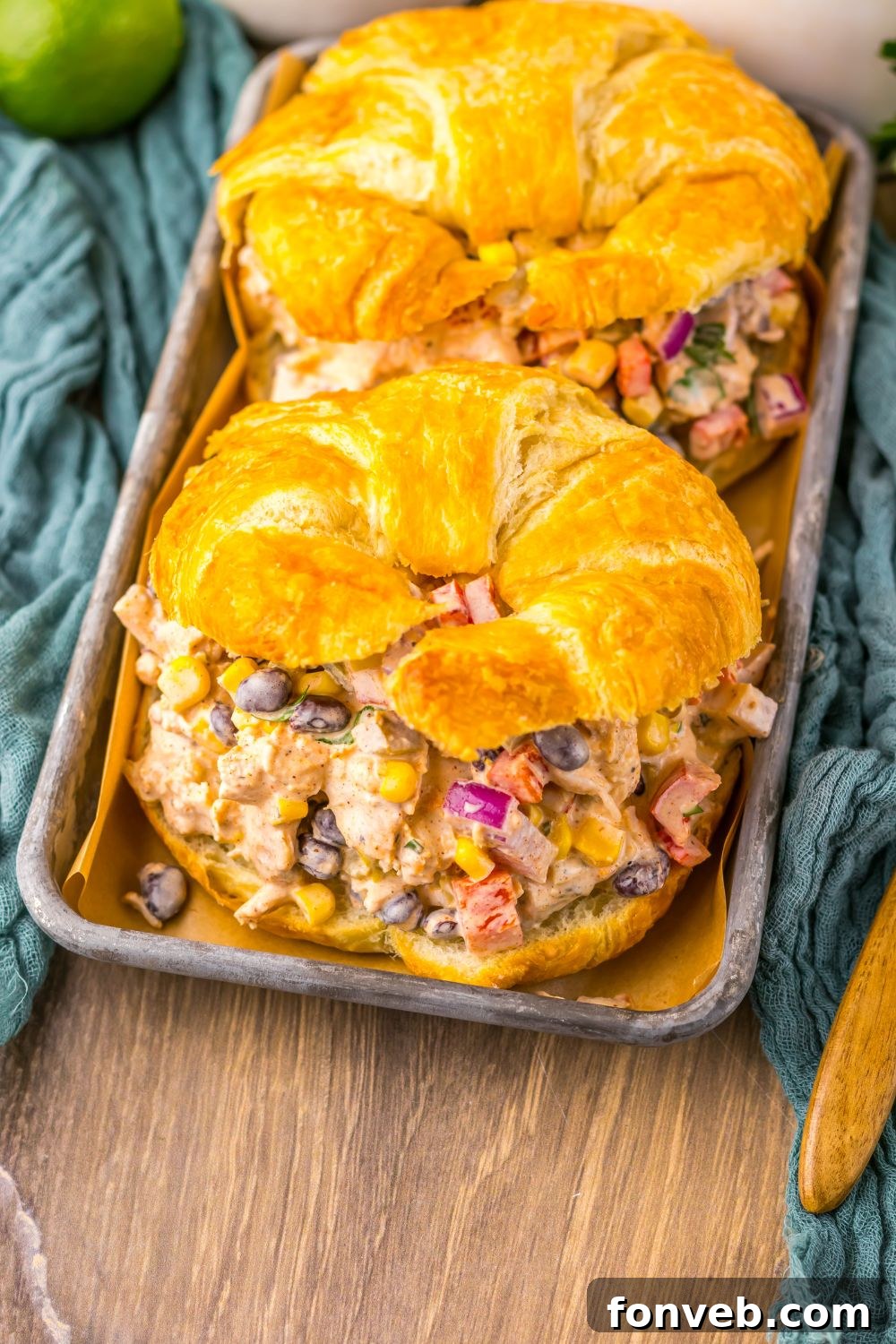 overhead look of table with Creamy Taco Chicken Salad sandwiches on plate with a towel on bottom of pan 