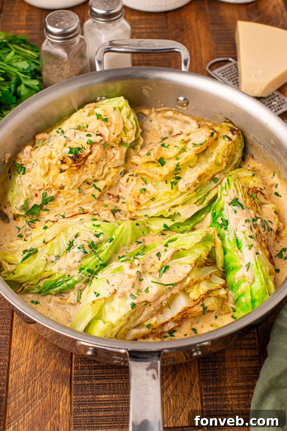Keto Creamy Garlic Parmesan Cabbage Skillet 12 Creamy Garlic Parmesan Cabbage in a skillet with a wedge of Parmesan cheese and seasoning