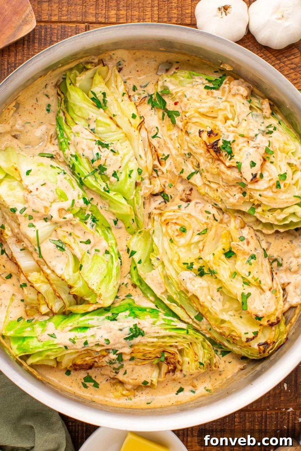 Keto Creamy Garlic Parmesan Cabbage Skillet 14 Creamy Garlic Parmesan Cabbage in a skillet with whole garlic bulbs on the side