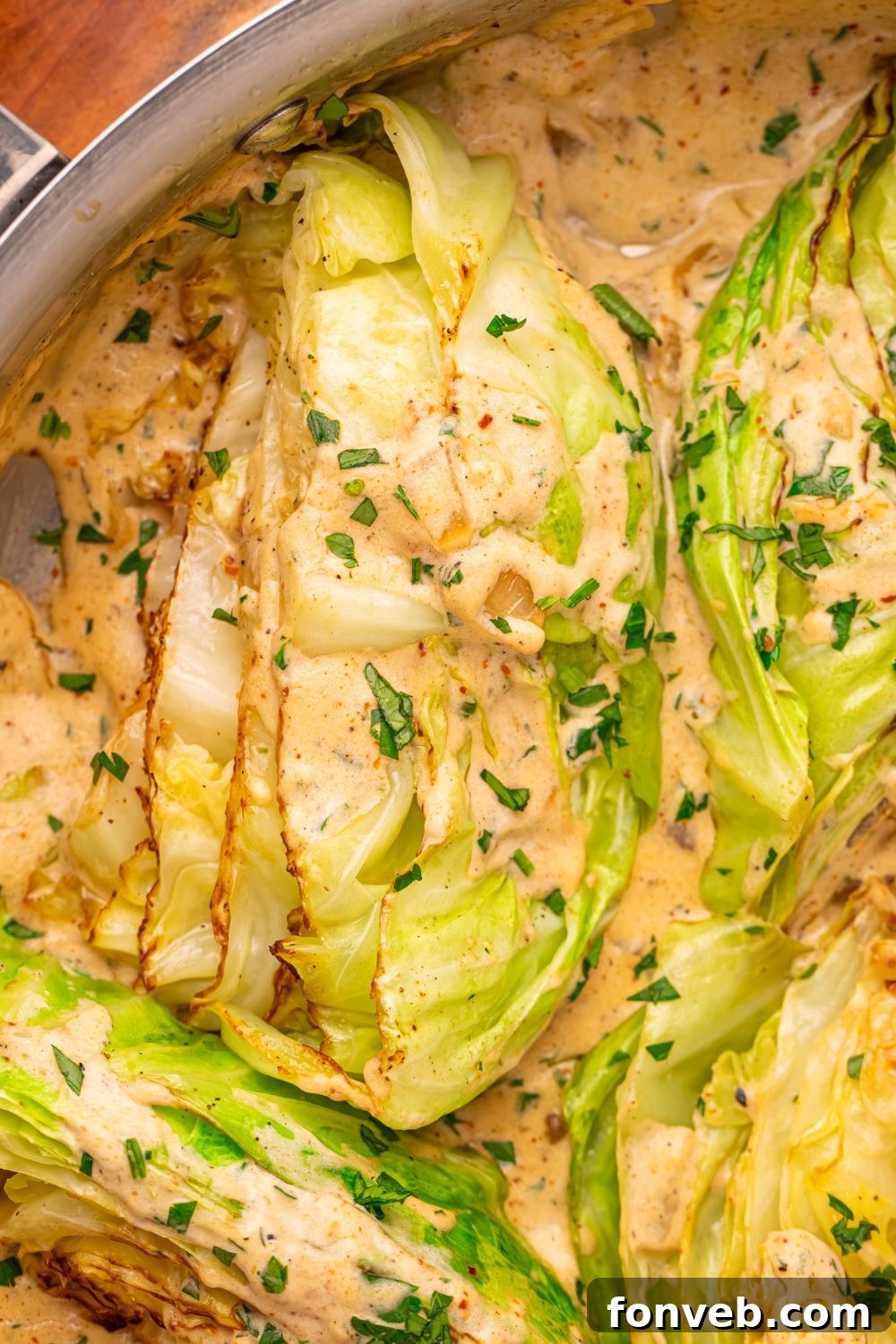 Keto Creamy Garlic Parmesan Cabbage Skillet 22 Creamy Garlic Parmesan Cabbage in a skillet on a table with parsley sprinkled on top
