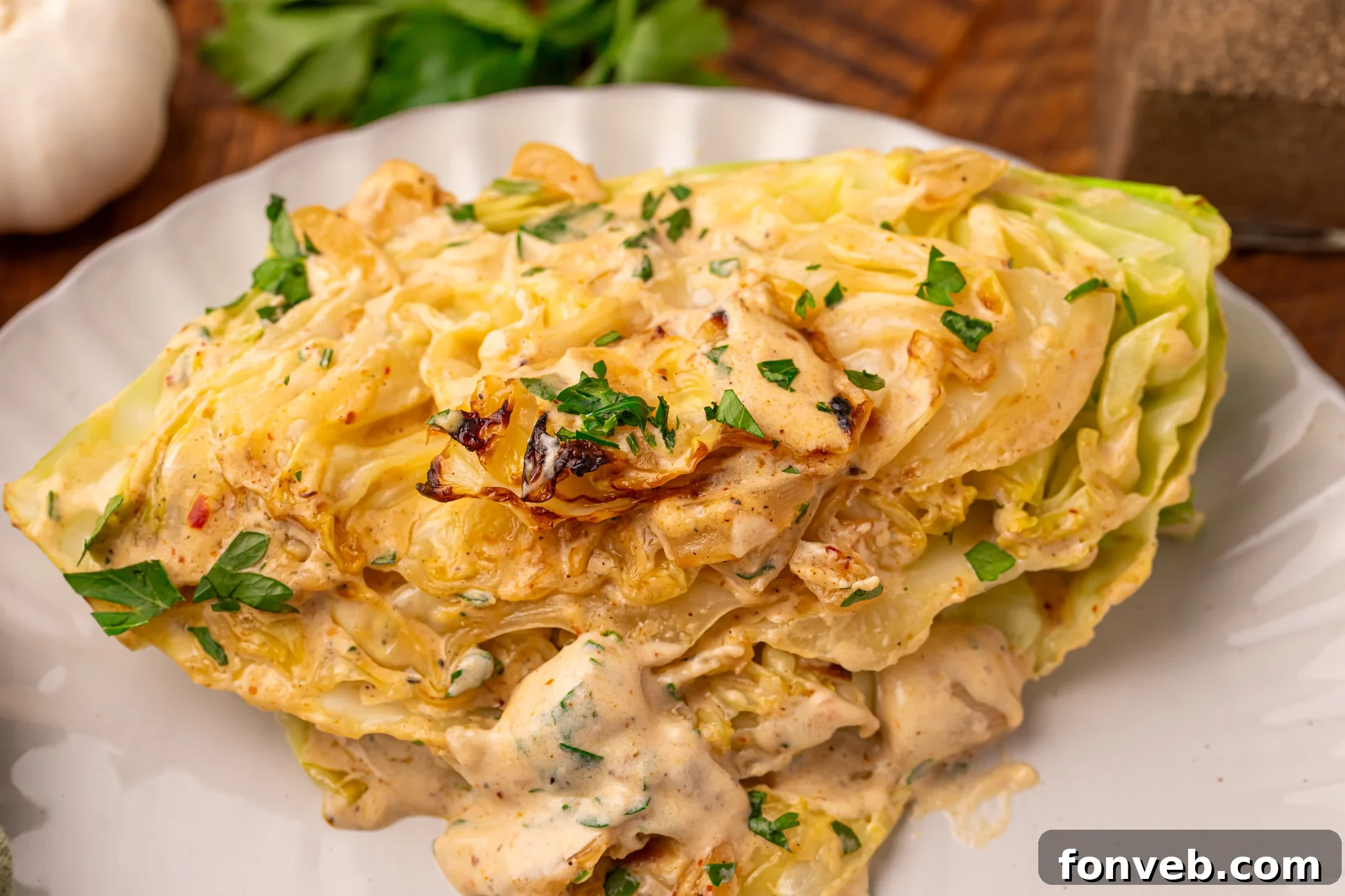 Keto Creamy Garlic Parmesan Cabbage Skillet 25 Creamy Garlic Parmesan Cabbage wedge on a white plate, close-up to show texture