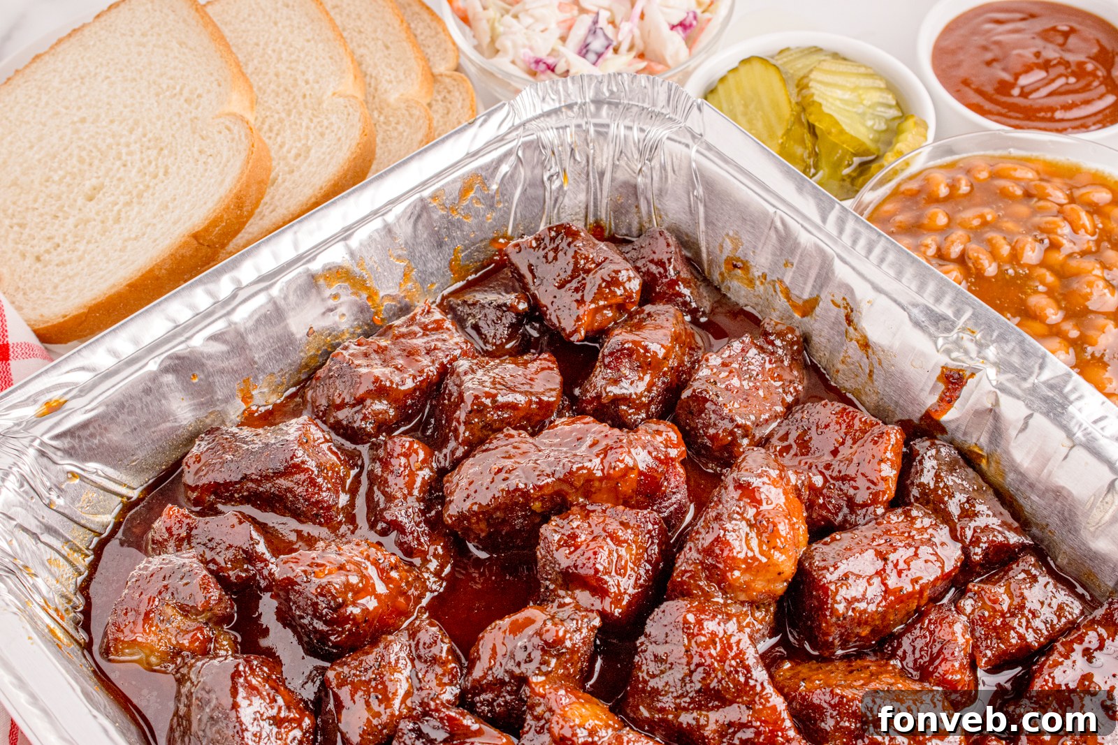 Chuck Roast Burnt Ends are piled high in a tin pan, their smoky glaze and tender texture a testament to delicious barbecue, ready to be served.