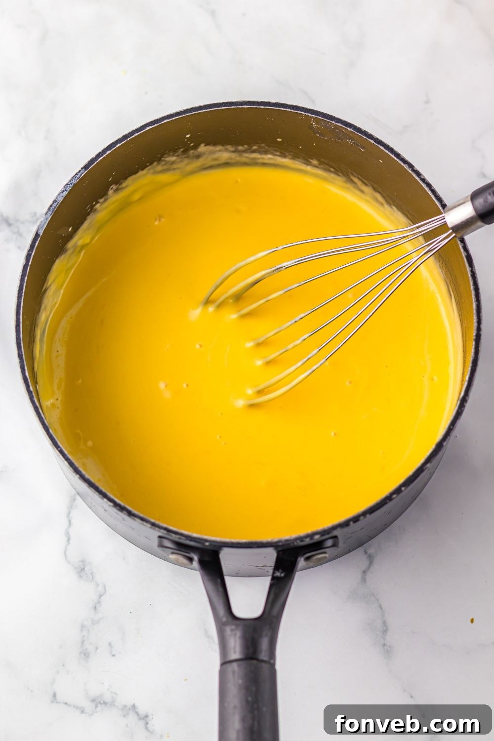 cheese sauce in a sauce pan with a whisk 