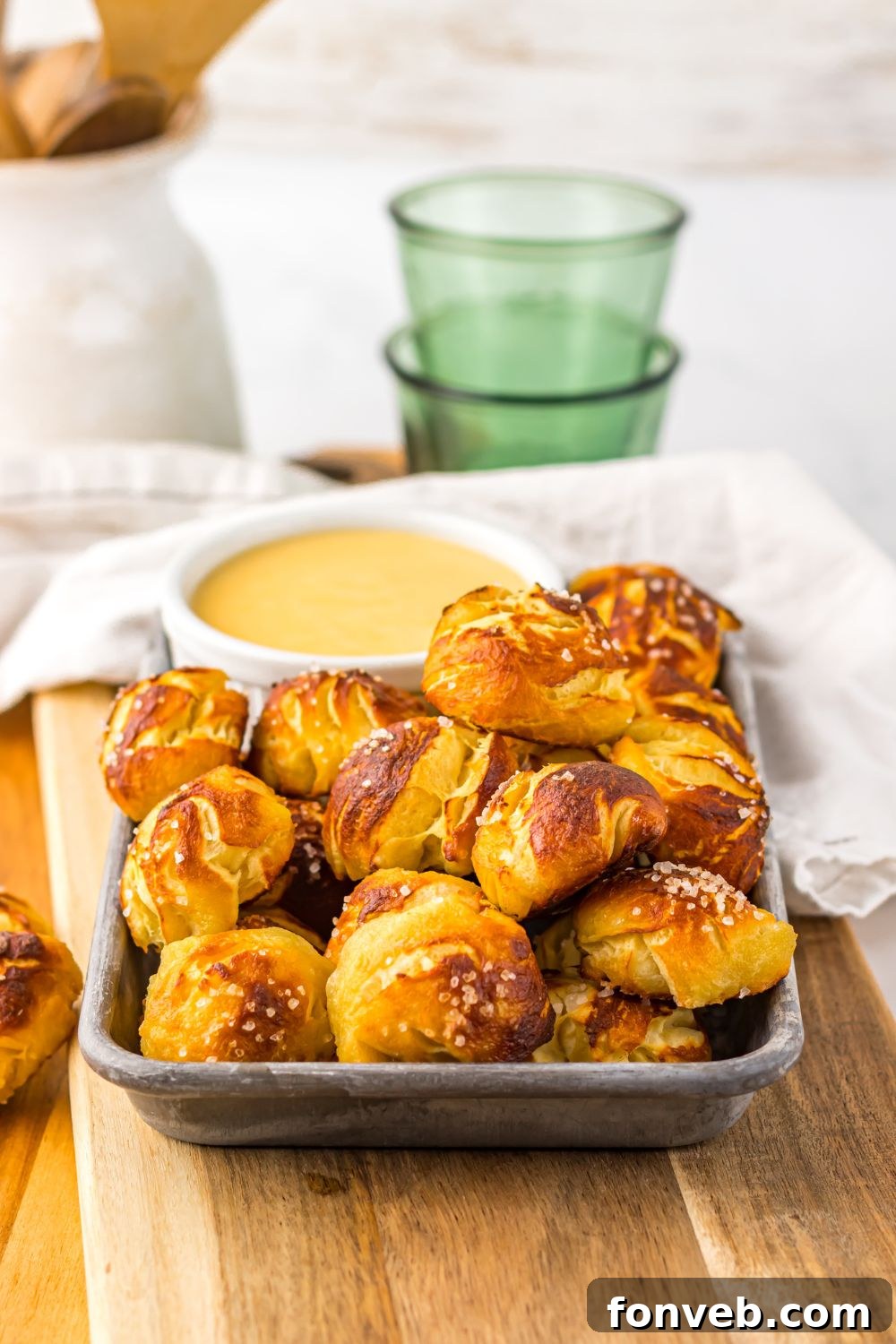 Easy Biscuit Pretzel Bites with Cheese Sauce on a tray with towel behind  it on table 