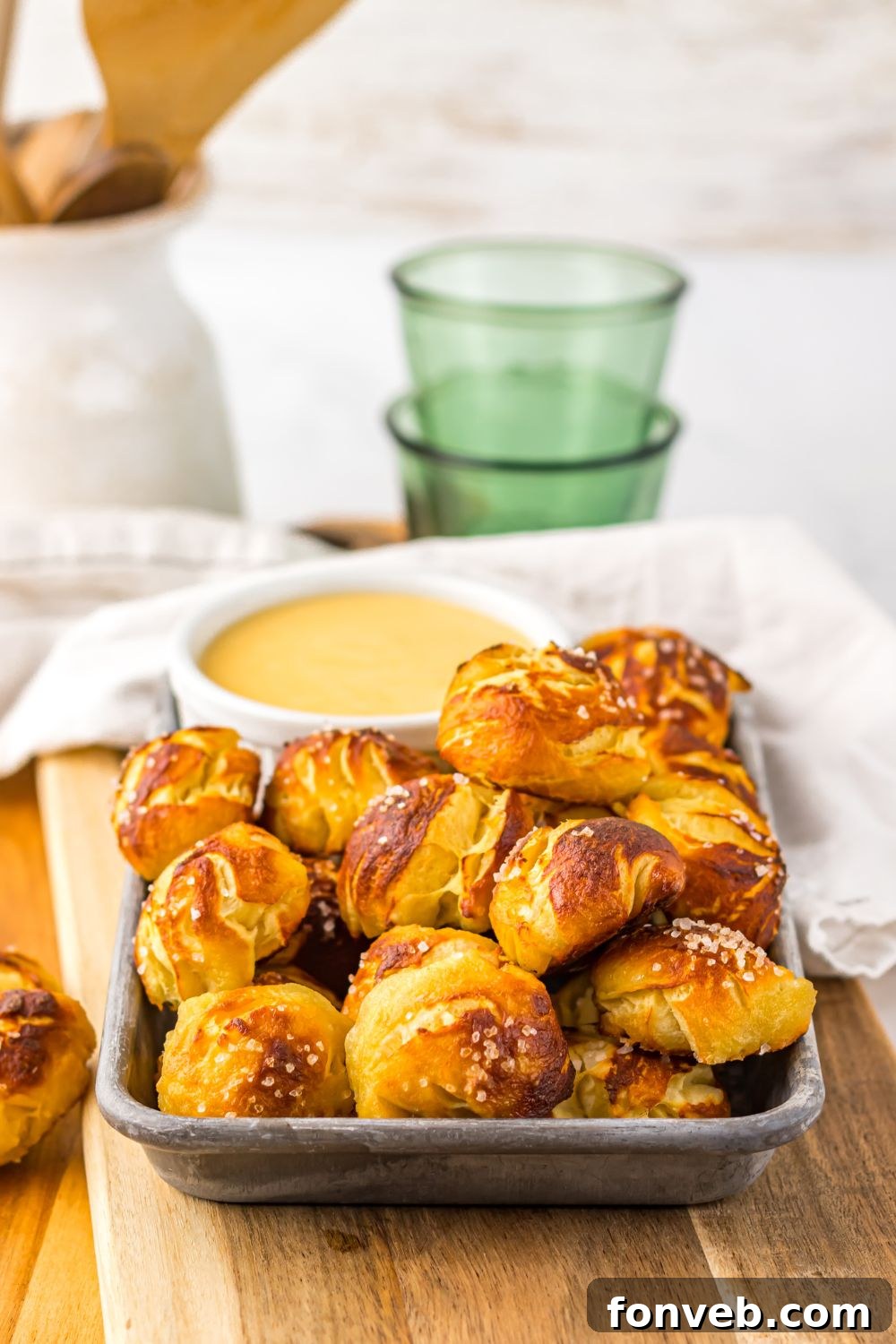 Easy Biscuit Pretzel Bites with Cheese Sauce on table with a towel and glass behind it on table 