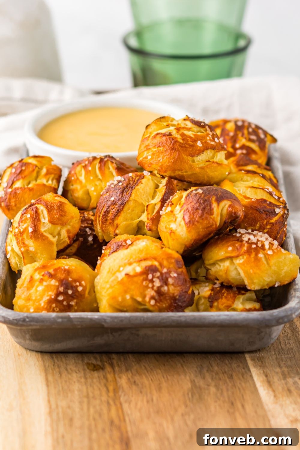 Easy Biscuit Pretzel Bites with Cheese Sauce sitting on tray with a green glass to side 
