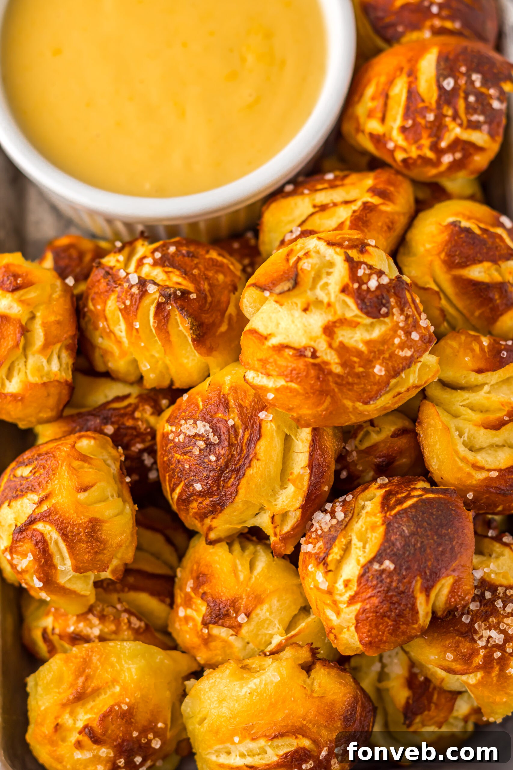 up close shot of the Easy Biscuit Pretzel Bites with Cheese Sauce in a white bowl next to it 