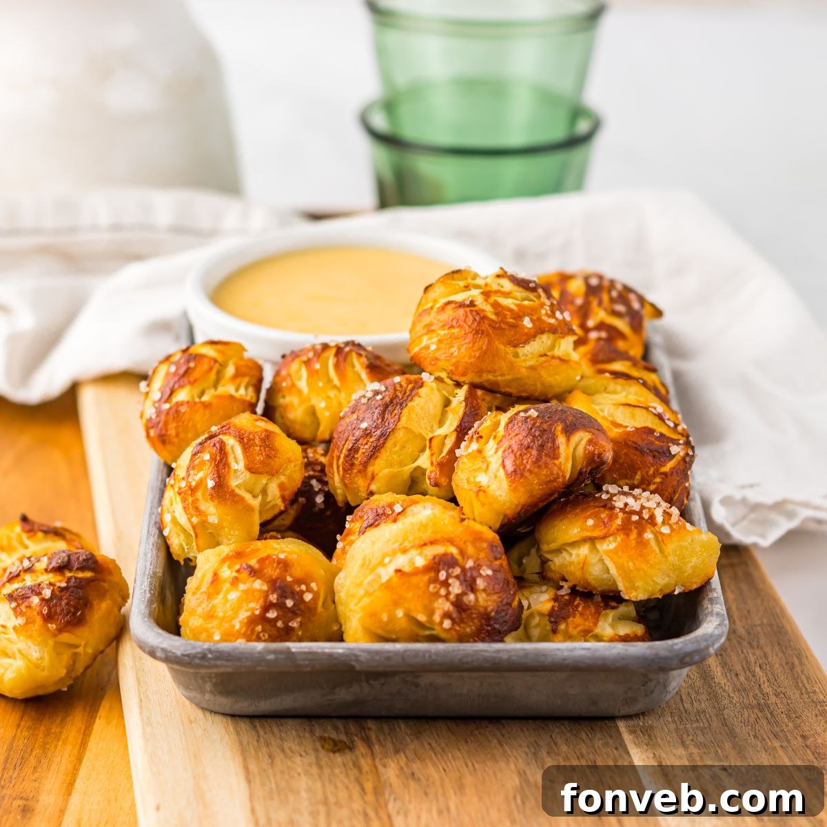Easy Biscuit Pretzel Bites with Cheese Sauce on a tray sitting on table with a glass to the side 